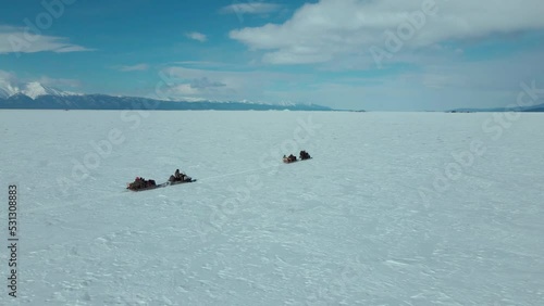 follow the train of snowmobiles in endless arctic landscape against blue sky photo