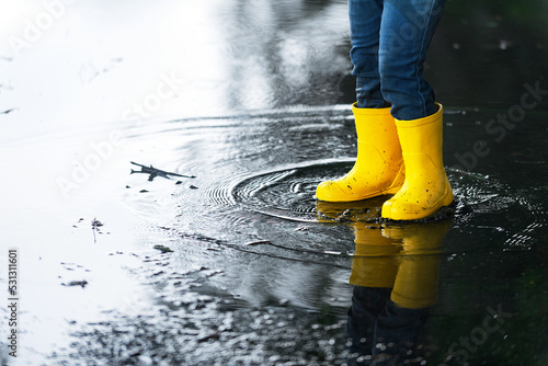 Schilderij op canvas the child plays and runs through the puddles in bright yellow rubber boots