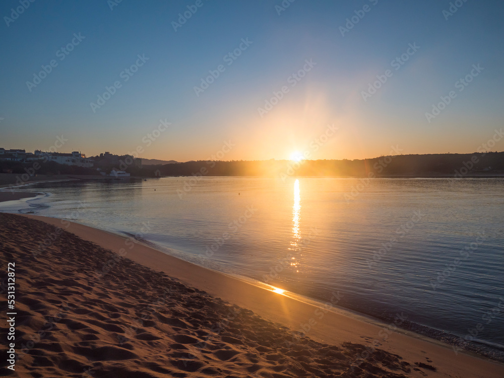 Φωτογραφία Orange sunrise at empty sand beach Praia da Franquia at Vila Nova de Milfontes with Mira river and fort Forte de Milfonte