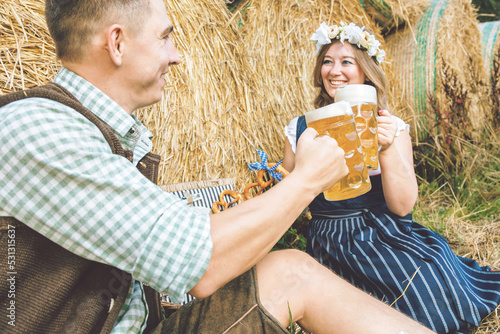 Young woman and man with beer glass and pretzel on wooden background .Oktoberfest concept