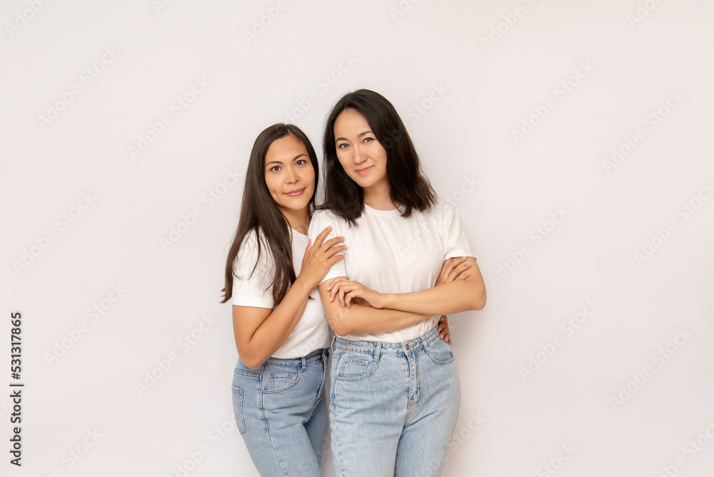 2 attractive brunette sisters or girlfriends on white background copy space. happy young asian women in white t-shirts 2 attractive brunette sisters or girlfriends on white background copy space. happy young asian women in white t-shirts