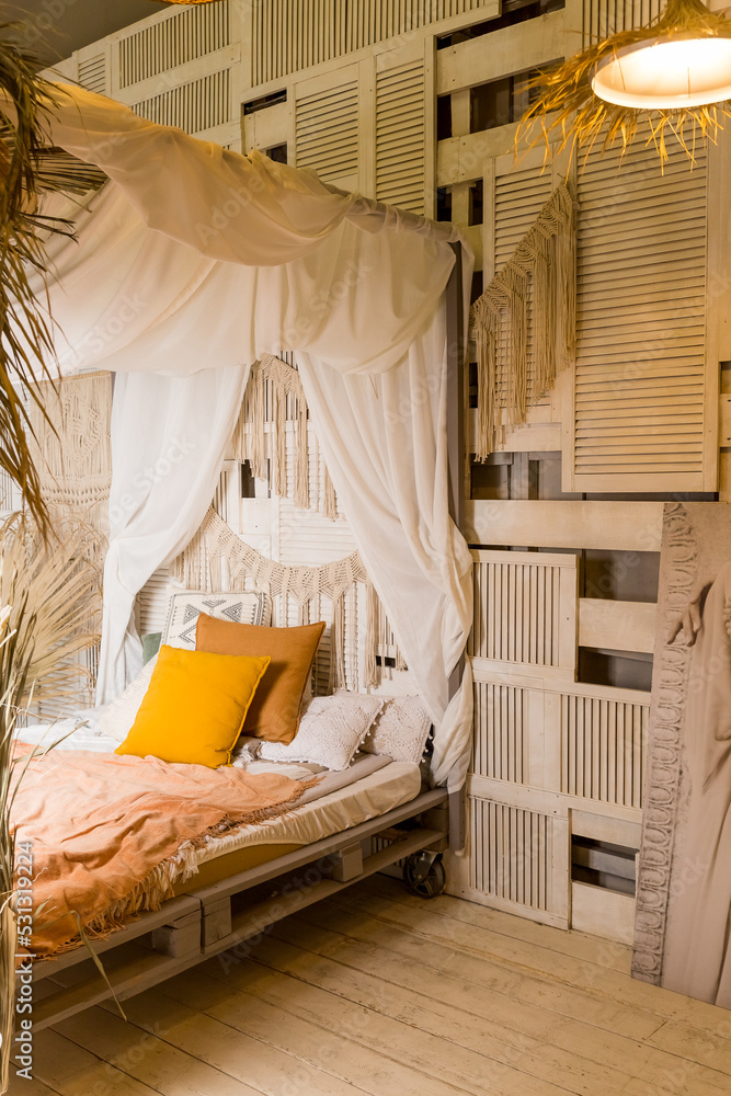 Modern home interior design. Bed with canopy and orange colored pillows,  blanket. bedroom interior, scandinavian style.Cozy room in apartment with  design in style of the boho chic. Comfortable bed Stock 写真