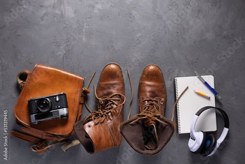 Travel stuff set and old boots on floor background texture. Trip goods as concept idea