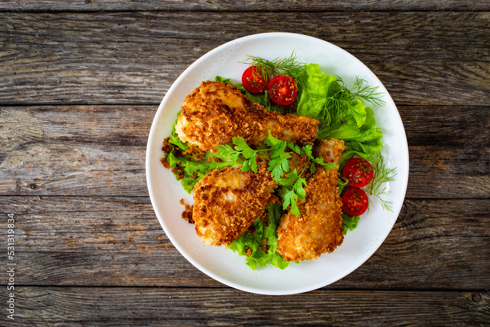 Panko crusted baked chicken drumsticks with greens on wooden table
Panko crusted baked chicken drumsticks with greens on wooden table