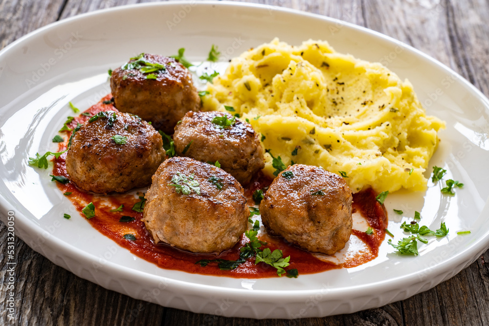 Fried pork meatballs with potato puree and tomato sauce on wooden table
Fried pork meatballs with potato puree and tomato sauce on wooden table