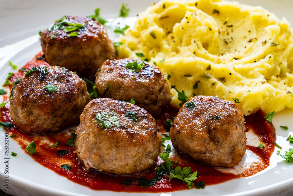 Fried pork meatballs with potato puree and tomato sauce on wooden table
