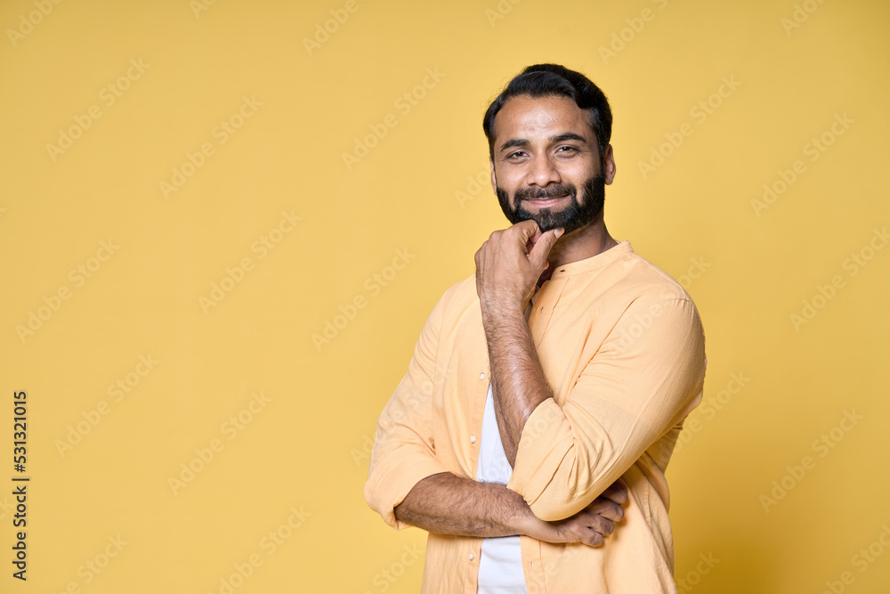 Confident rich bearded indian man standing isolated on yellow background. Happy handsome ethnic guy wearing shirt looking at camera advertising products thinking on offer for portrait. Confident rich bearded indian man standing isolated on yellow background. Happy handsome ethnic guy wearing shirt looking at camera advertising products thinking on offer for portrait.