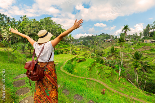 Obraz na plátně Young girl with hat standing with open arms looking the ricefields