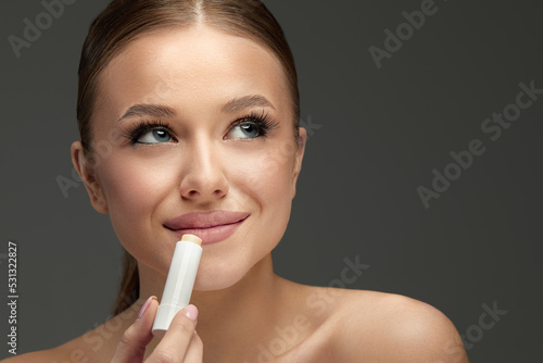 Lips Skin Care. Beautiful Woman Face With Lips Applying Hygienic Lip Balm, Lip Care Stick. Closeup Of Female Face With Soft Skin Putting Lip Protector Lipstick On. Beauty Cosmetics Concept.