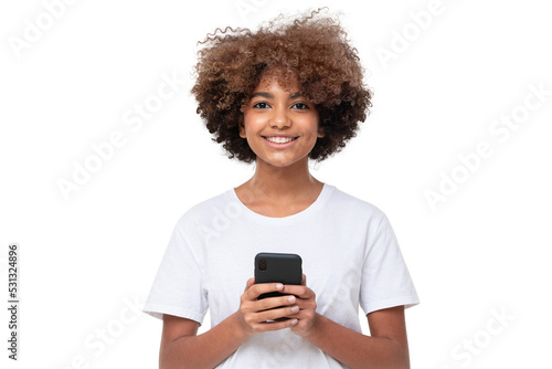 African american smiling teenage girl with afro hairstyle holding phone with both hands, chatting with friend, using social media app