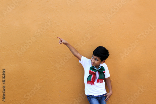 Latino Mexican boy shows discounts and promotions with his tricolor bow to celebrate the national holidays of Independence and Revolution
