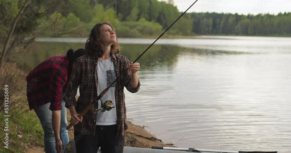 Young woman with spinning and her boyfriend on the lake are fishing. Young woman with spinning and her boyfriend on the lake are fishing.
