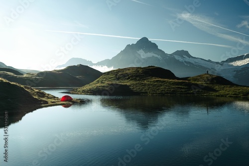 Fototapeta Beautiful landscape with a red tent on a lakeshore among mountains