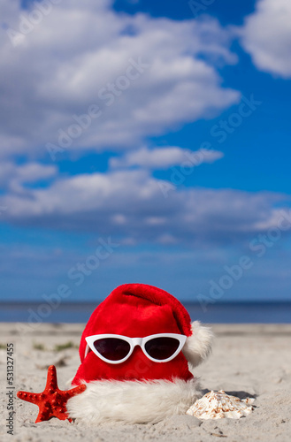 Christmas background Santa Claus hat on the beach with starfish and sunglases