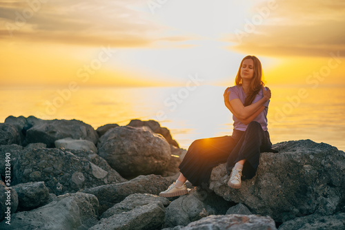 portrait of a woman hugging herself at sunset in summer by the sea
