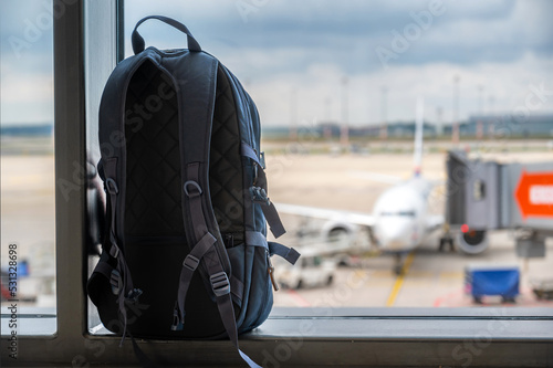 Fototapete Rucksack am Terminal eines Flughafens mit Ausblick auf ein Flugzeug