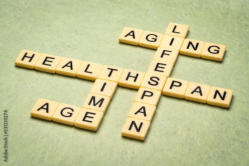 aging, time, lifespan and healthspan crossword in ivory letter tiles against textured handmade paper, age and longevity concept