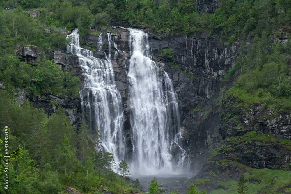 Wonderful landscapes in Norway. Hordaland. Beautiful scenery of Skjervsfossen waterfall from the Storelvi river on the Hardanger scenic route. Mountains, trees in background. Rainy day Selective focus