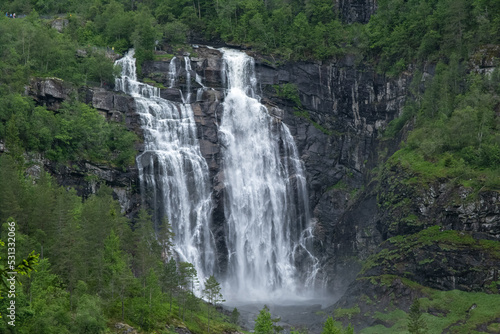 Wonderful landscapes in Norway. Hordaland. Beautiful scenery of Skjervsfossen waterfall from the Storelvi river on the Hardanger scenic route. Mountains  trees in background. Rainy day Selective focus