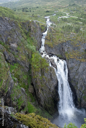 Wonderful landscapes in Norway. Vestland. Beautiful scenery of Voringfossen waterfall in the Mabodalen valley on the Hardanger scenic route. Mountains, trees in background. Cloudy day. Selective focus