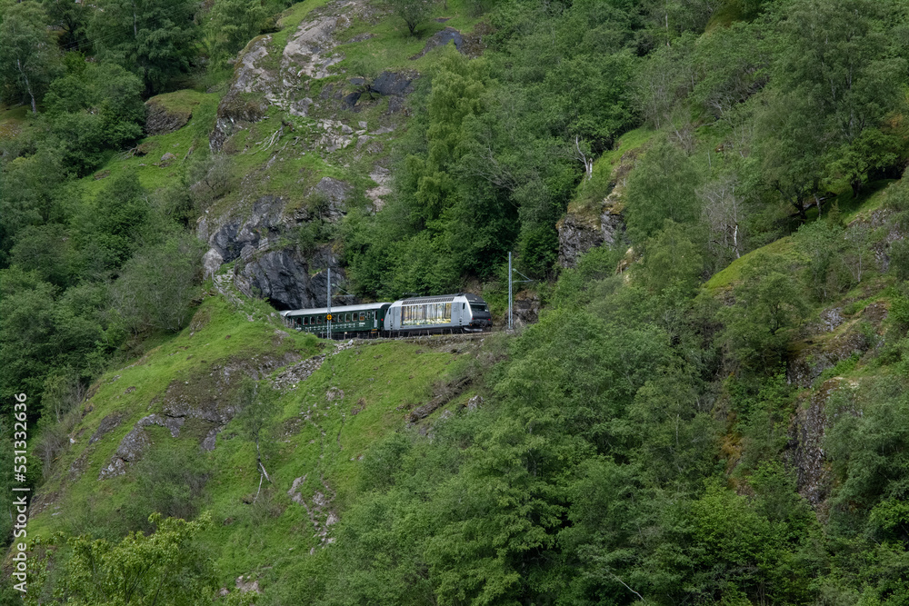 Flam, Norway - June 19, 2022: Flamsbana is a railway line between Myrdal and Flam in Aurland Municipality. Vestland. It runs through the valley of Flamsdalen. Cloudy spring day. Selective focus