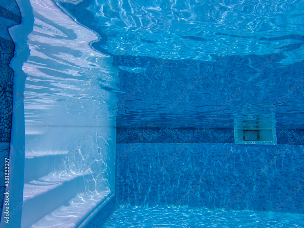 Underwater view of tranquil blue swimming pool with white steps