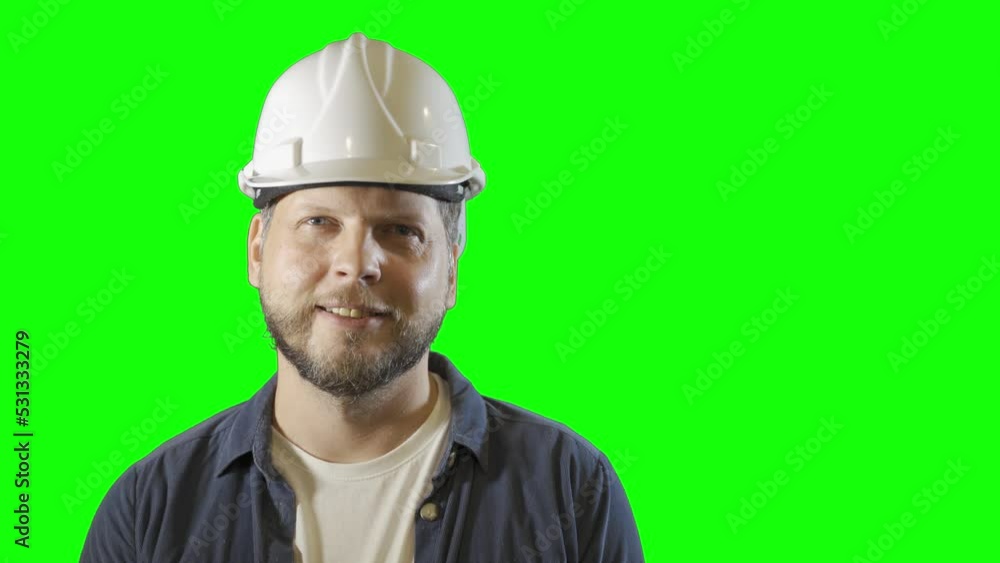 a male engineer worker in a construction helmet smiles portrait on a green background a male engineer worker in a construction helmet smiles portrait on a green background