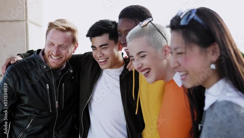 Diverse group of united young friends laughing together outdoor - Multiracial teenager students having fun hugging each other in street - Team, community and unity concept photo