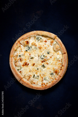 Pizza with four cheeses, mozzarella, blue cheese, Parmesan cheese. Italian cuisine on black background. View from above.