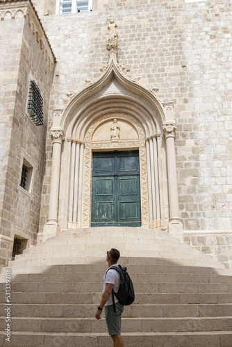 Man looks at weathered green door marks the Iconic entrance to the Dominican Monastery was listed UNESCO World Heritage. King's Landing, capital Seven Kingdoms in the old town of Dubrovnik, Croatia