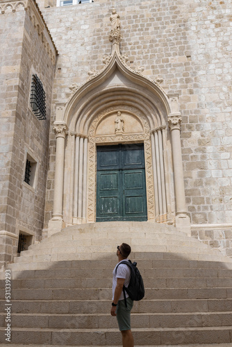 Man looks at weathered green door marks the Iconic entrance to the Dominican Monastery was listed UNESCO World Heritage. King's Landing, capital Seven Kingdoms in the old town of Dubrovnik, Croatia © Евгения Жигалкина
