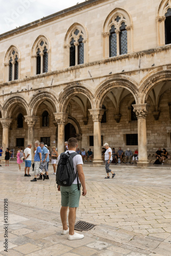 Dubrovnik, Croatia - September 21, 2021. Man stands at Gothic Rector's palace with Renaissance arched constructions. Old town was listed UNESCO World Heritage. King's Landing, capital Seven Kingdoms