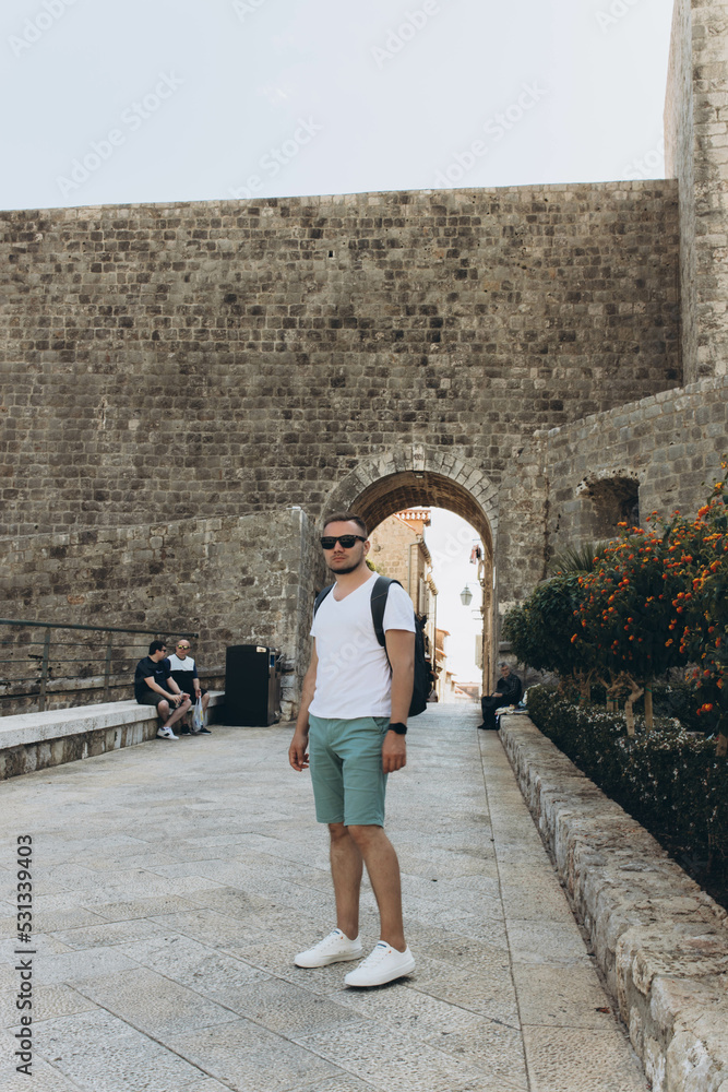 Man stands at one of the entrance Facade gates to the old walled town of Dubrovnik, Croatia. Fortress controlling and protecting the port. capital Seven Kingdoms, show Game of Thrones.