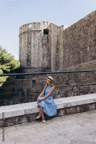Lady sits at one of the entrance Facade gates to the old walled town Dubrovnik, Croatia. Fortress controlling and protecting the port. capital Seven Kingdoms, show Game of Thrones. Traveling, tourism