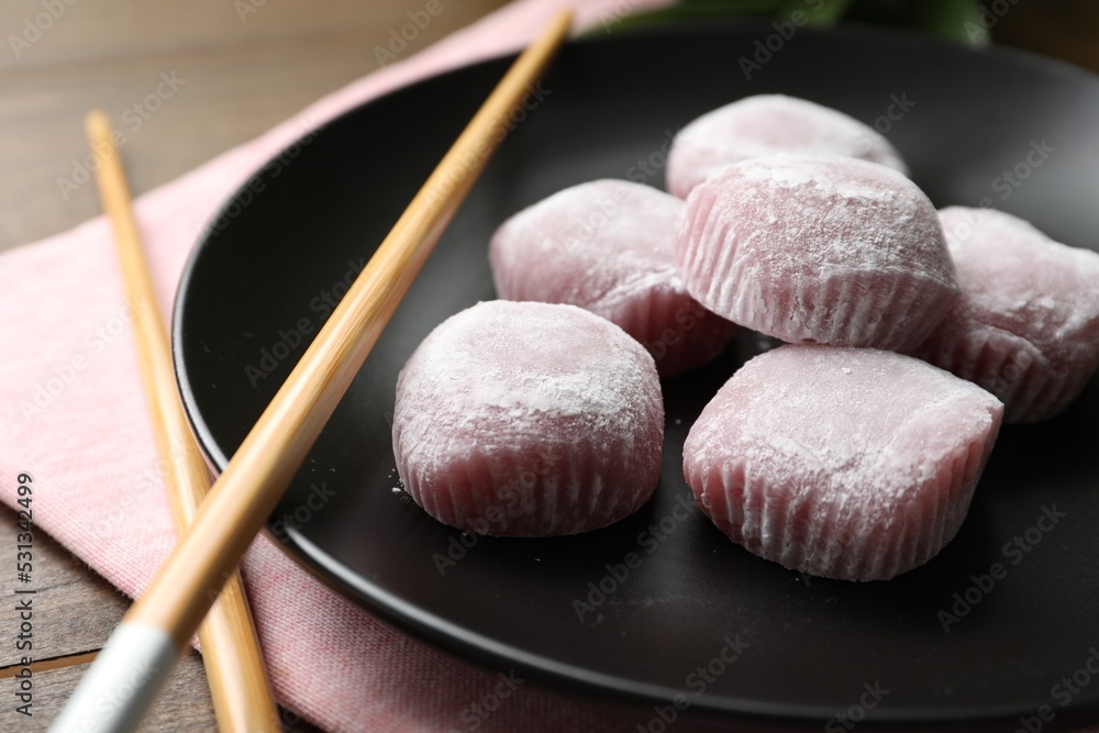 Black plate with delicious mochi and chopsticks on wooden table, closeup. Traditional Japanese dessert Black plate with delicious mochi and chopsticks on wooden table, closeup. Traditional Japanese dessert