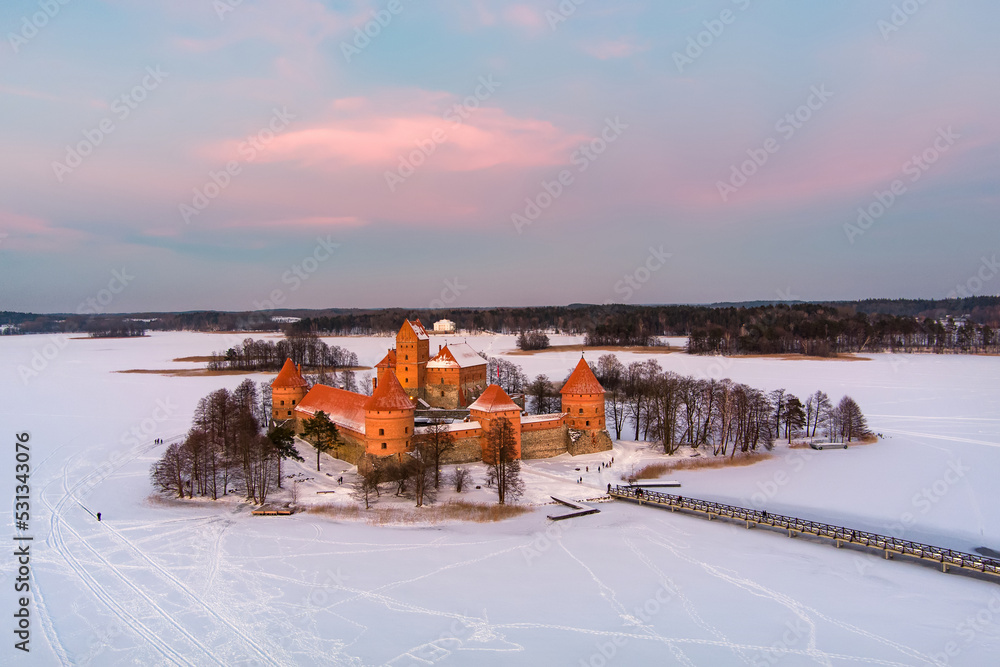 Beautiful aerial view of Trakai Island Castle, located in Trakai, Lithuania. Snow covered Galve lake on sunny winter sunrise. Beautiful aerial view of Trakai Island Castle, located in Trakai, Lithuania. Snow covered Galve lake on sunny winter sunrise.