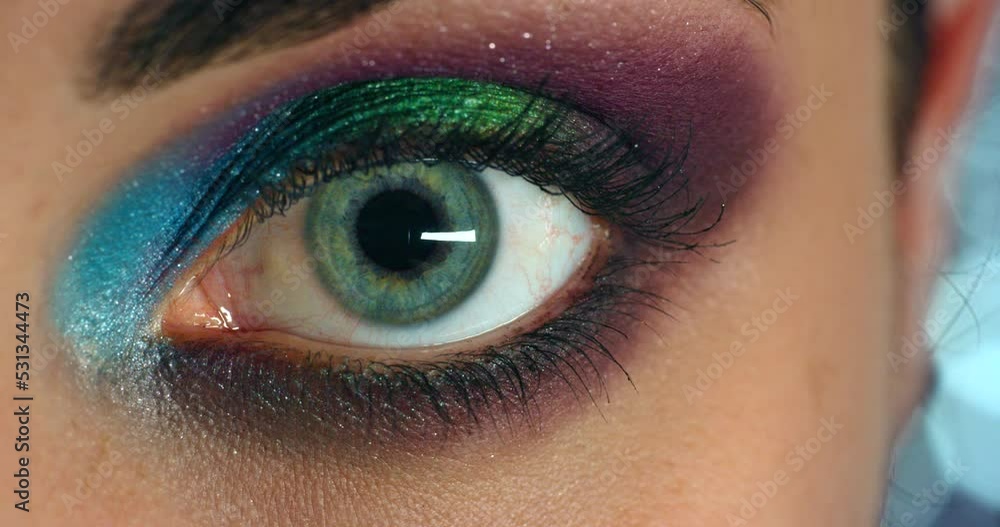 Creative makeup, eye cosmetics and woman with rainbow art on face, splash of color and vision of artist on model against background with blue bokeh. Portrait of girl with professional designer beauty Creative makeup, eye cosmetics and woman with rainbow art on face, splash of color and vision of artist on model against background with blue bokeh. Portrait of girl with professional designer beauty