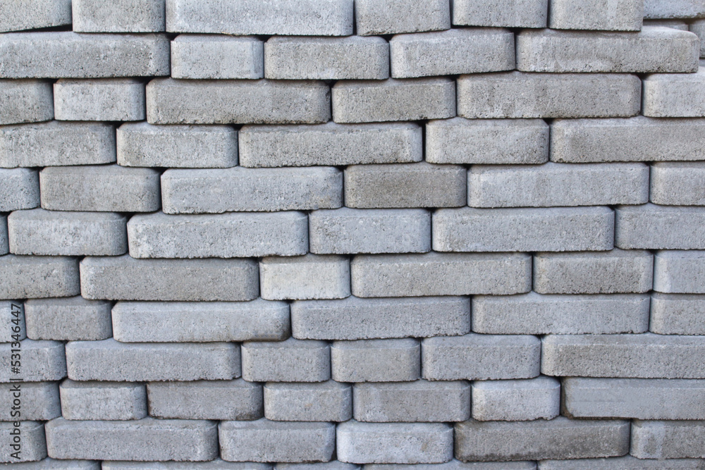 Defocus brick tiles stacked on a pallet. Gray pavement bricks for pavement road. Stack paving stones stacked in stacks. Gray design copy space. Brick background. Out of focus Defocus brick tiles stacked on a pallet. Gray pavement bricks for pavement road. Stack paving stones stacked in stacks. Gray design copy space. Brick background. Out of focus