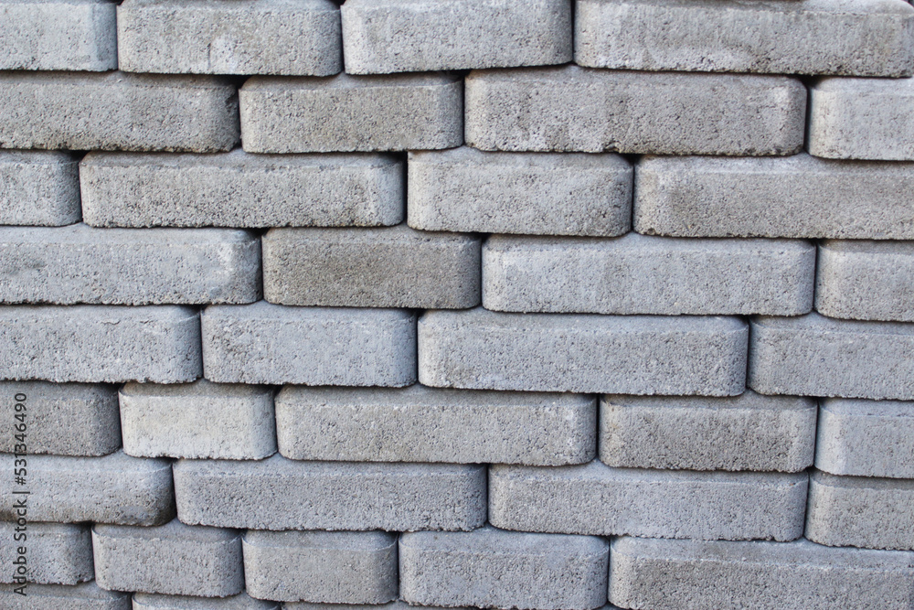 Defocus brick tiles stacked on a pallet. Gray pavement bricks for pavement road. Stack paving stones stacked in stacks. Gray design copy space. Out of focus Defocus brick tiles stacked on a pallet. Gray pavement bricks for pavement road. Stack paving stones stacked in stacks. Gray design copy space. Out of focus