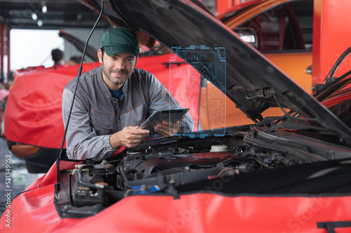 car service ,repair, maintenance concept - Arab auto mechanic man or Smith checking the car performance via  tablet at workshop warehouse before start repair/tunnig the car in the garage photo