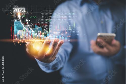 Businessman holding growth a graph to years 2023 virtual screen on hand to analyze for investment. Analysis and plan investments for business profit goals. Business, Investment, and Finance concept.