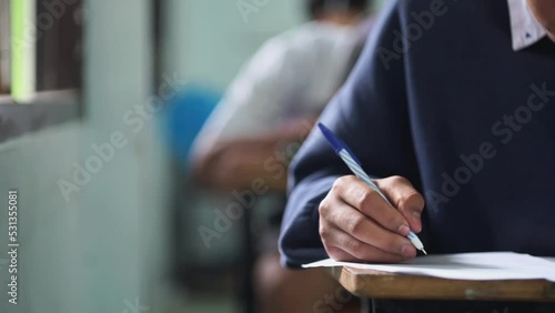 Close up hand of students reading and taking exam sheets exercises answer with stress in classroom