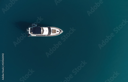 Aerial yacht on calm sea. Luxury cruise trip. View from above of white boat on deep blue water. Aerial view of rich yacht sailing sea. Summer journey on luxury ship. © panophotograph