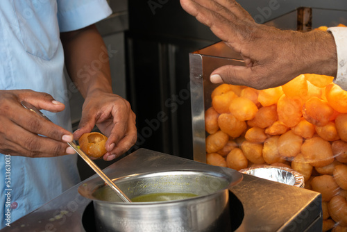 A man serving pani puri at street food stall. Vendor, chat, masala, spicy, clean, hygienic, unhealthy, labor, fry, hot, cold, puchka, batasha, water, mint, chutney photo