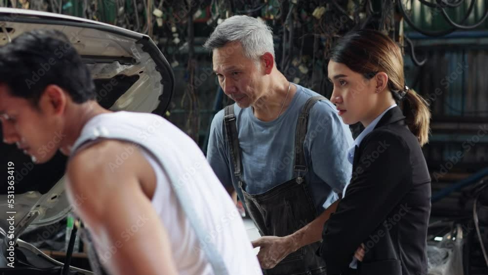 Serious asian young woman customer talking with owner and mechanic worker at car repair service and auto store shop. Serious asian young woman customer talking with owner and mechanic worker at car repair service and auto store shop.