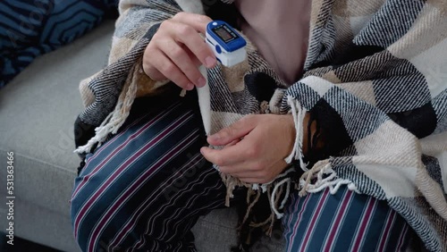 Young man with pulse oximeter on hand measuring oxygen saturation level at home. Pulseoxymeter medical device, pulseoxymetry clip machine monitorin ox rate. Close up of hand and pulse oximeter photo