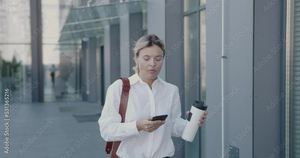 Business Person Holding Coffee To Go Hurry to Work. Senior Businesswoman Going Fast On Street. Mature Female Holding Hot Beverage Near Office Building. Business and Lifestyle Concept Business Person Holding Coffee To Go Hurry to Work. Senior Businesswoman Going Fast On Street. Mature Female Holding Hot Beverage Near Office Building. Business and Lifestyle Concept