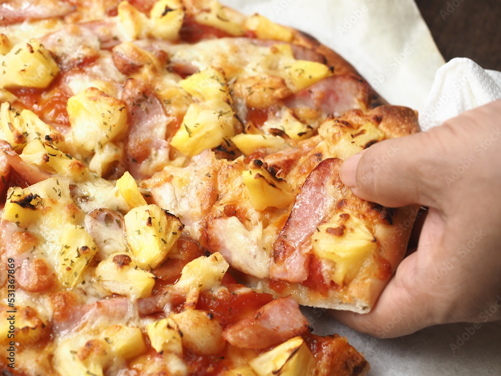 hand taking a piece of Hawaiian pizza hand taking a piece of Hawaiian pizza