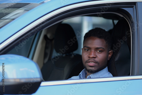 African American driver sits in car cabin. Serious businessman enjoys life, looking at camera © lenblr