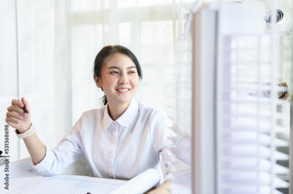 Asian woman smart architect look out the window to rest one's eyes or relax while working in light and bright office room, Concentrate on work and idea management, Working on architect-designer jobs. Asian woman smart architect look out the window to rest one's eyes or relax while working in light and bright office room, Concentrate on work and idea management, Working on architect-designer jobs.